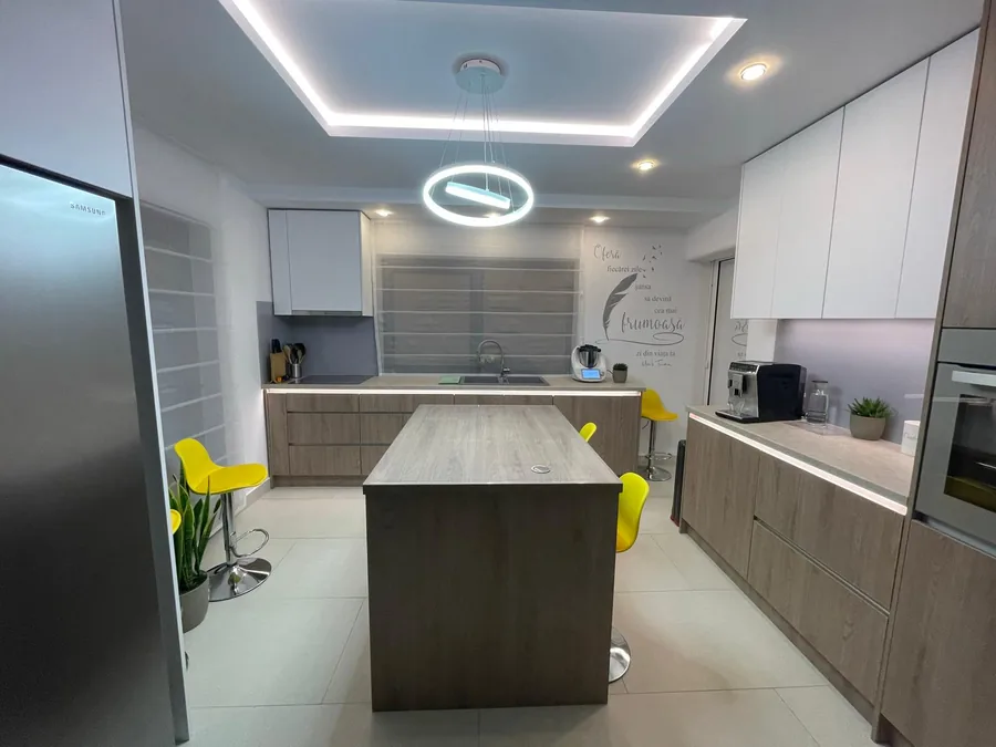 Modern kitchen with large fridge and yellow bar stools
